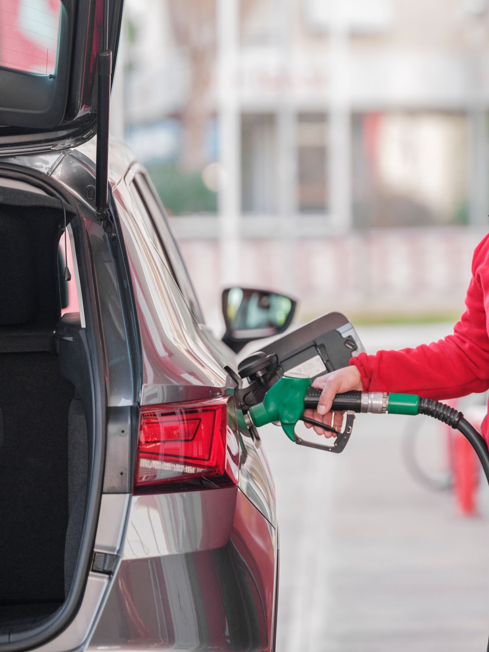 Person refuelling a car at a fuel station, illustrative stock photo