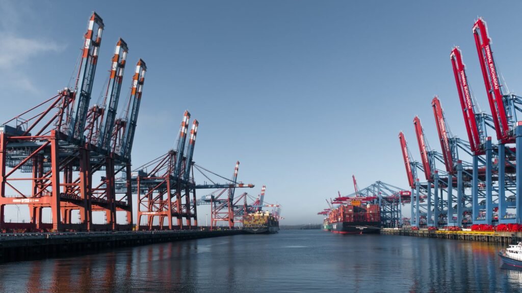 Container ship and cranes at a busy shipping port, illustrative stock photo